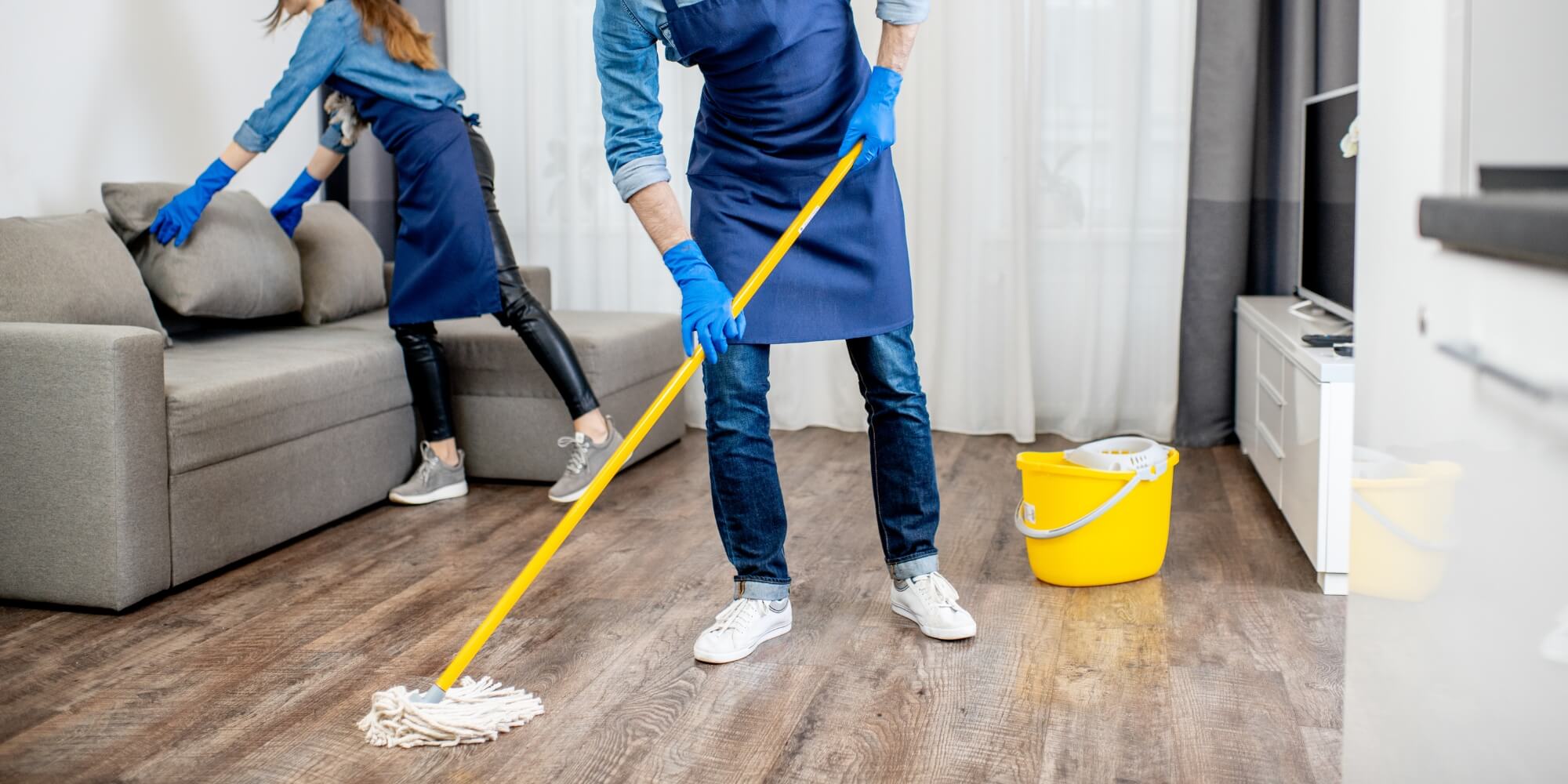 Smiling cleaning technicians cleaning the hardwood floor